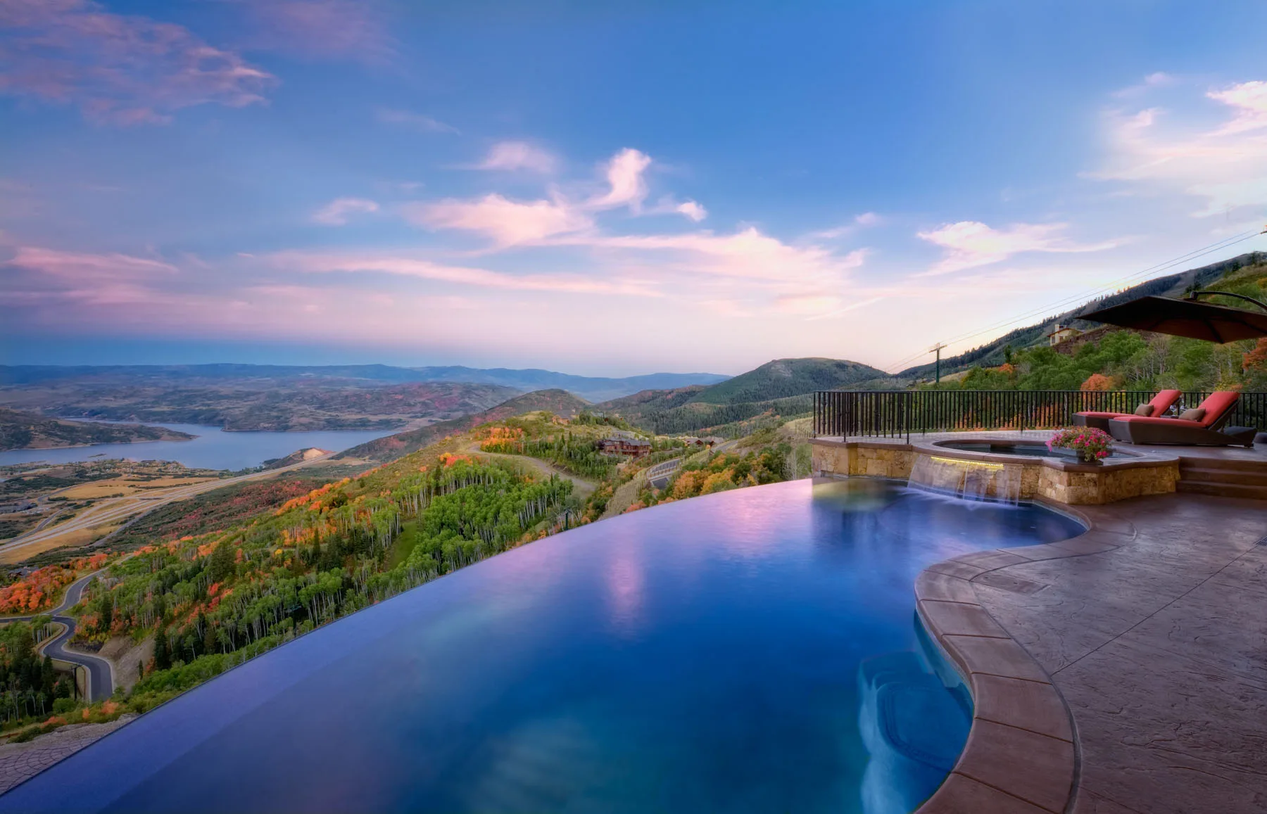 Infinity-edge pool at dusk with mountain views and loungers along the deck