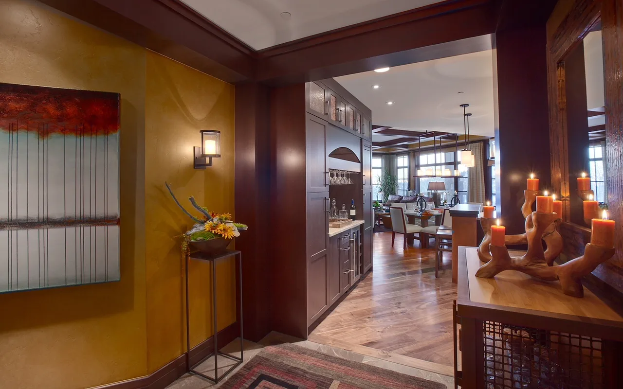 View through an archway into a dining area with wood cabinetry and candles on a console table