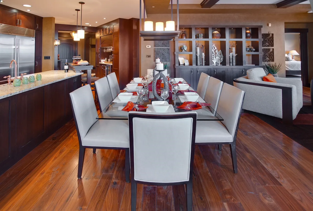 Dining room set with a red and white table setting, candles, wood chairs and a cluster pendant light