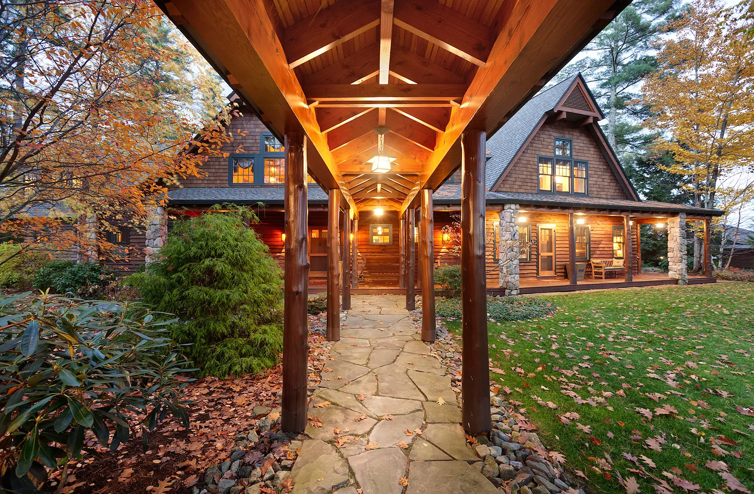 Covered timber-beamed breezeway with stone pillars leading toward the house entrance