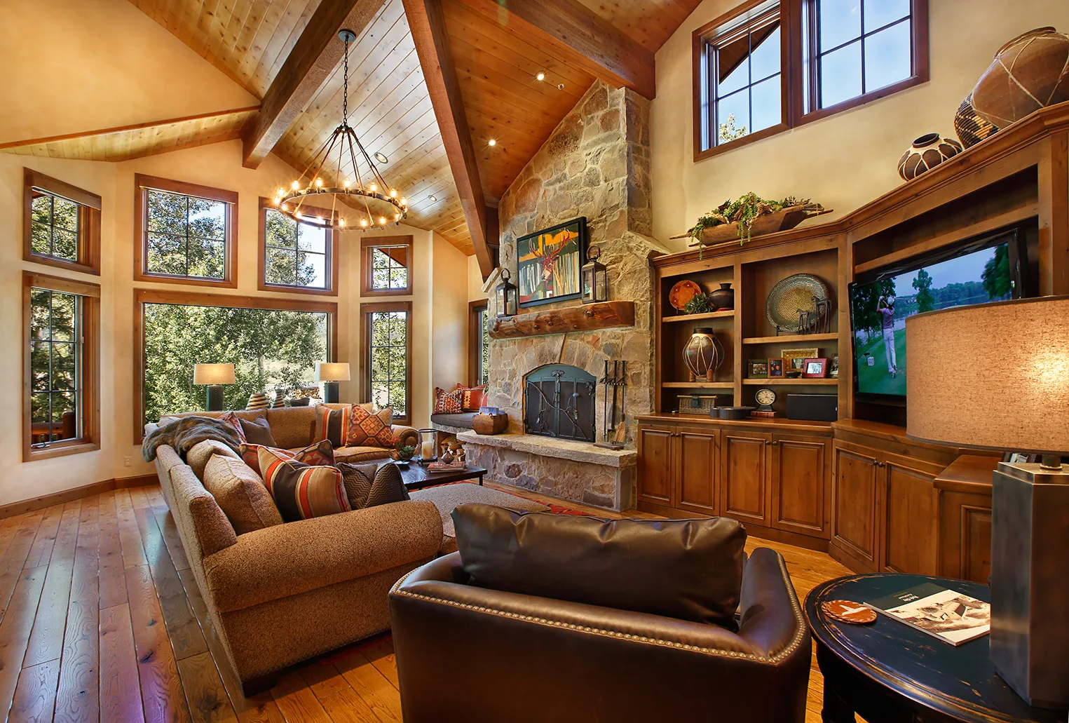Living room with a stone fireplace, built-in shelving, a mounted TV and leather furniture