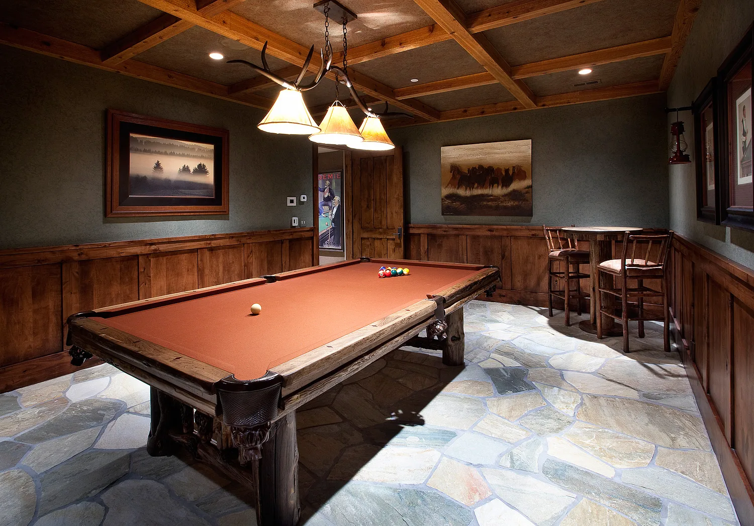 Game room with a pool table, a bar area and stone accent walls
