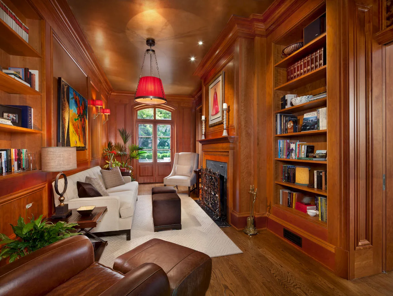 Library with wood paneling, built-in bookshelves, leather chairs and a fireplace