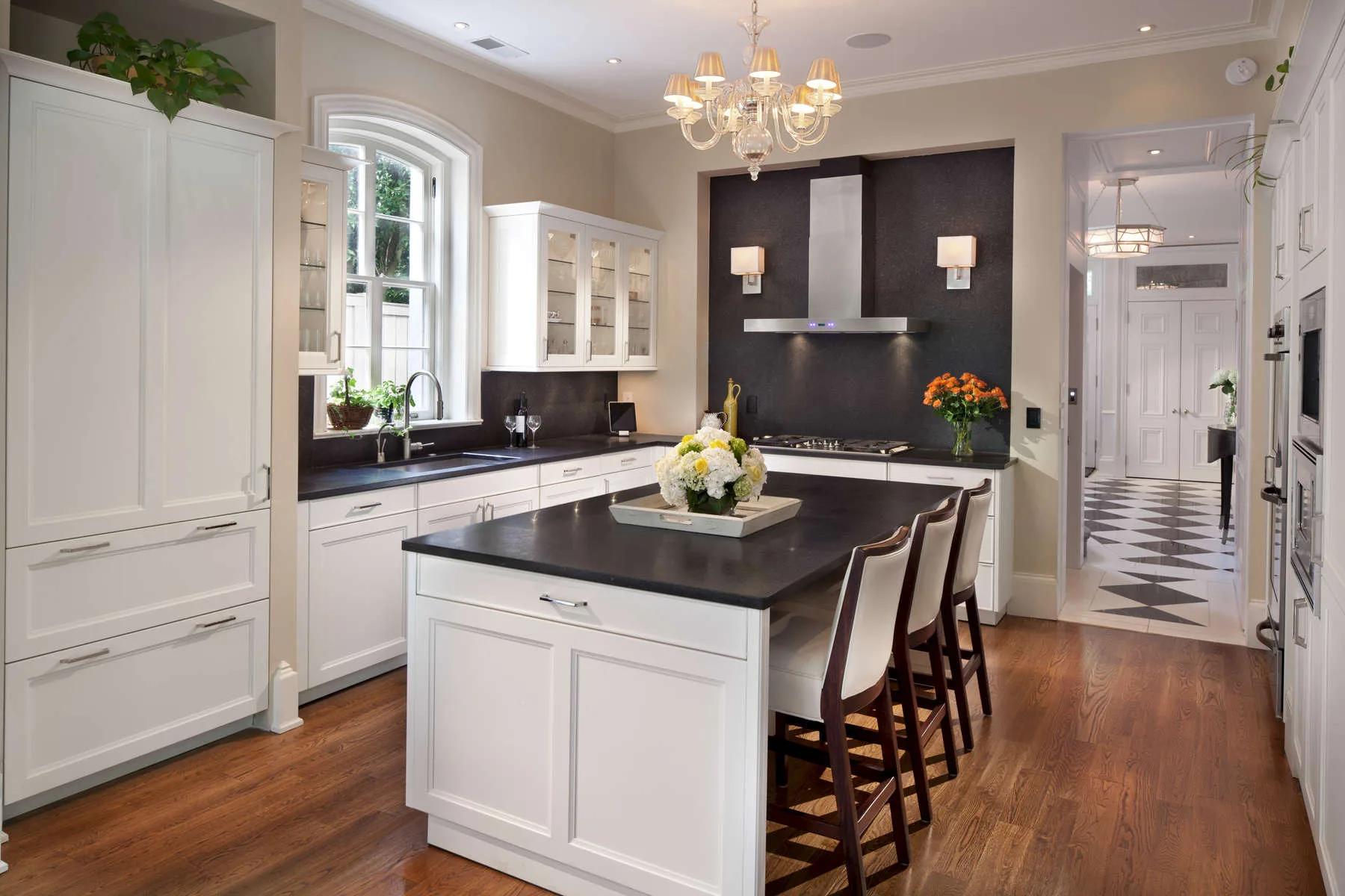 Kitchen with white cabinetry, dark countertops and a wood range hood