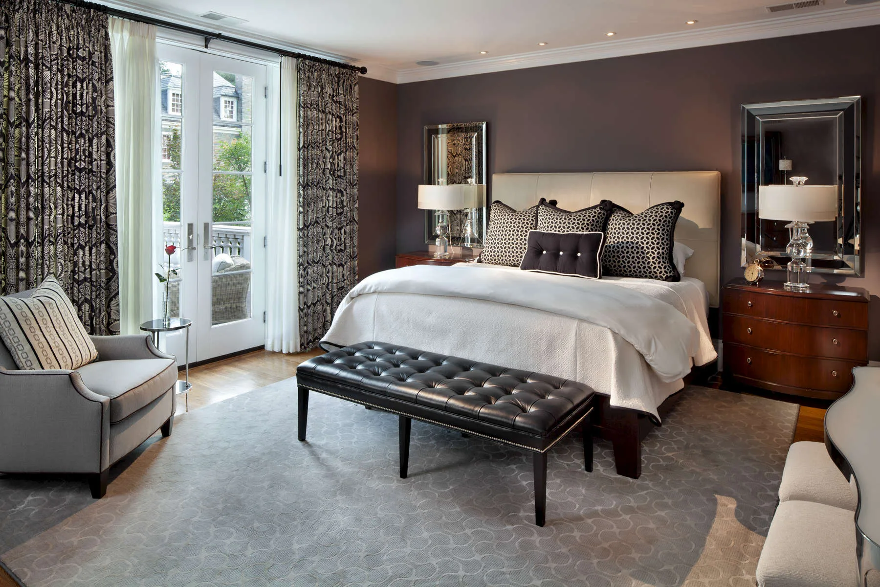 Bedroom with an upholstered bench, gray tones and French doors opening to a balcony
