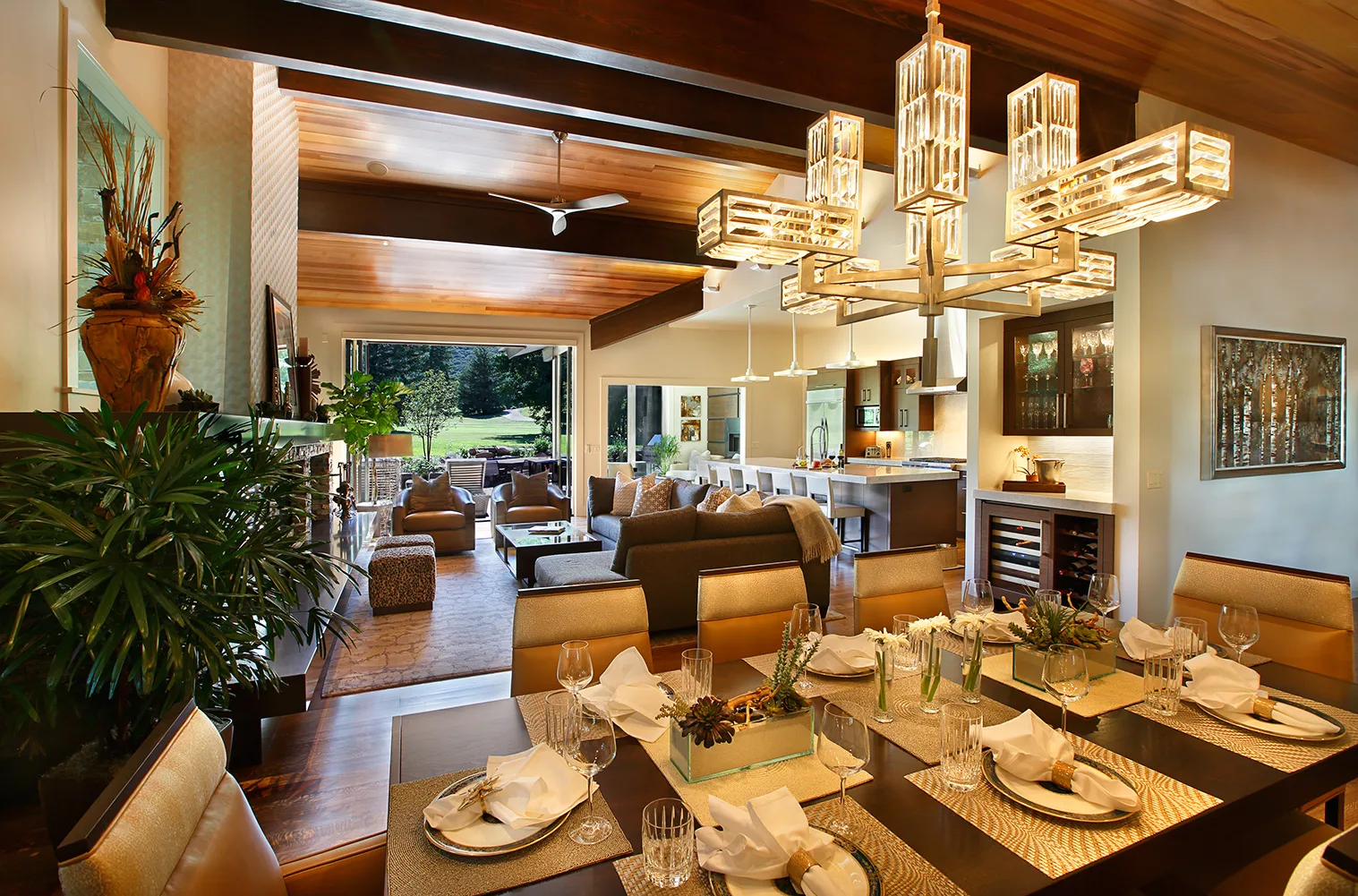 Dining room with a multi-tier modern chandelier, exposed wood beam ceiling and a table set for dinner