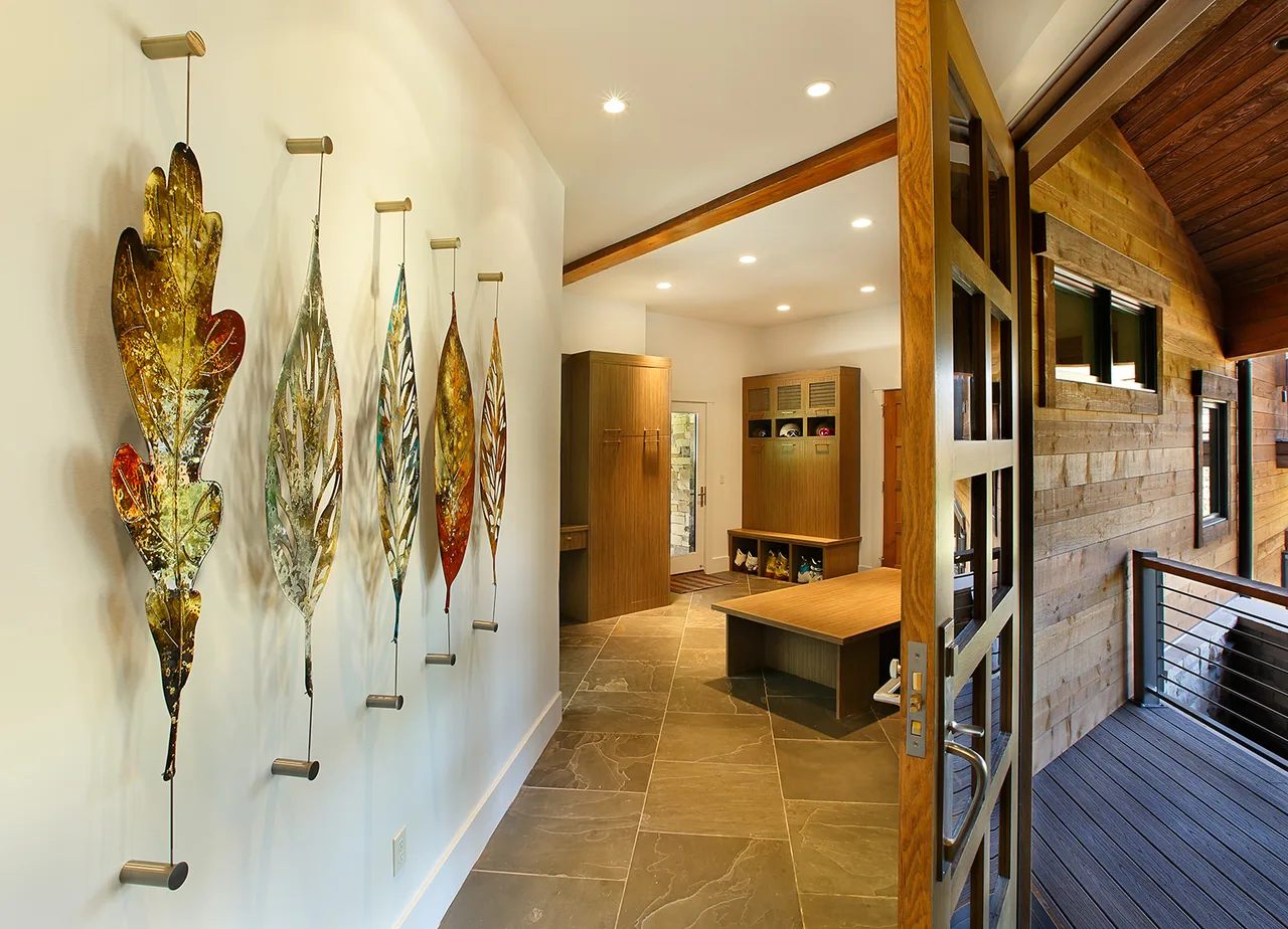 Narrow hallway with a stone tile floor, wall art and a bench