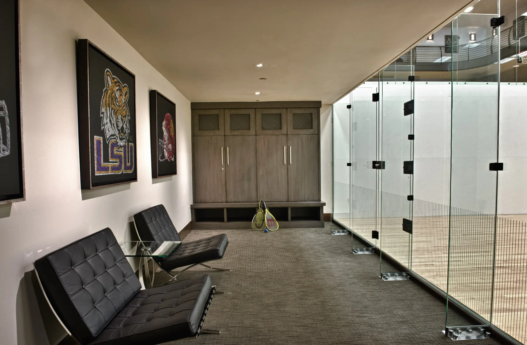 Den with built-in dark wood cabinetry, two black leather chairs and framed art