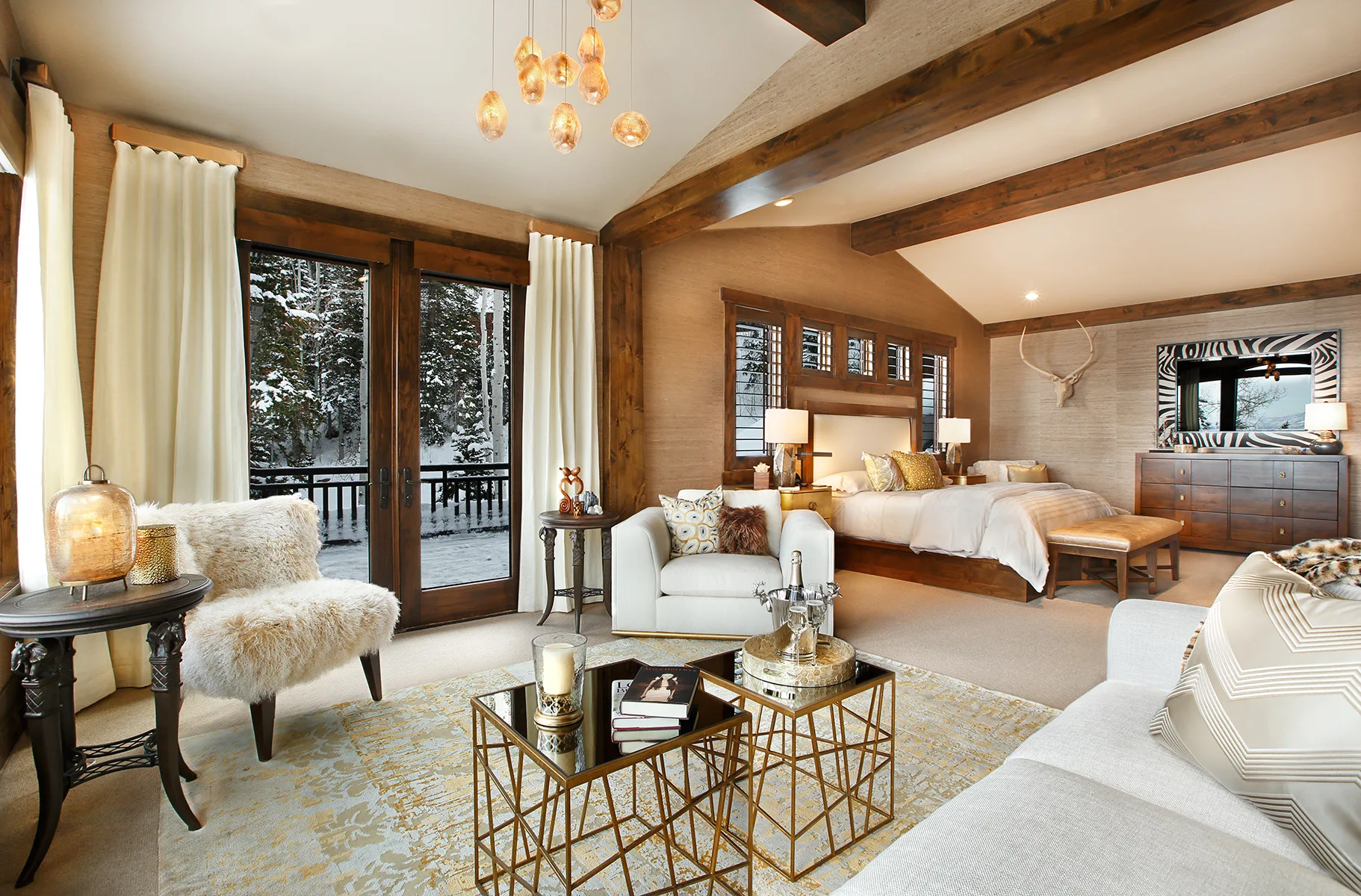 Sitting area with a cream sofa and chairs under a string-light fixture, large windows opening to a deck