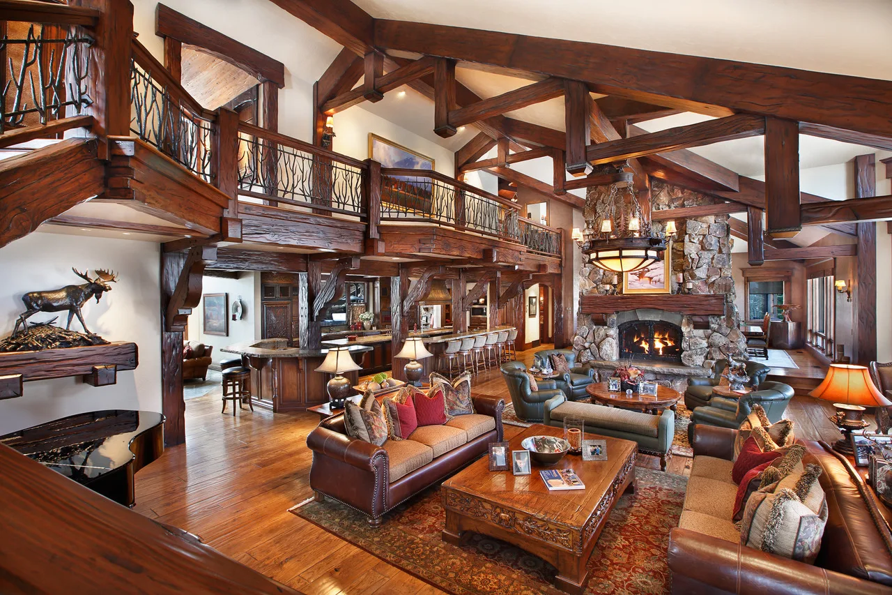 Loft balcony overlooking a great room below, with wood railings and a taxidermy mount on the wall