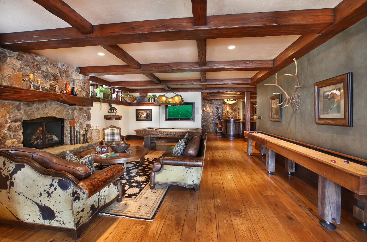 Living room with a stone fireplace, wood beam ceiling and leather furniture