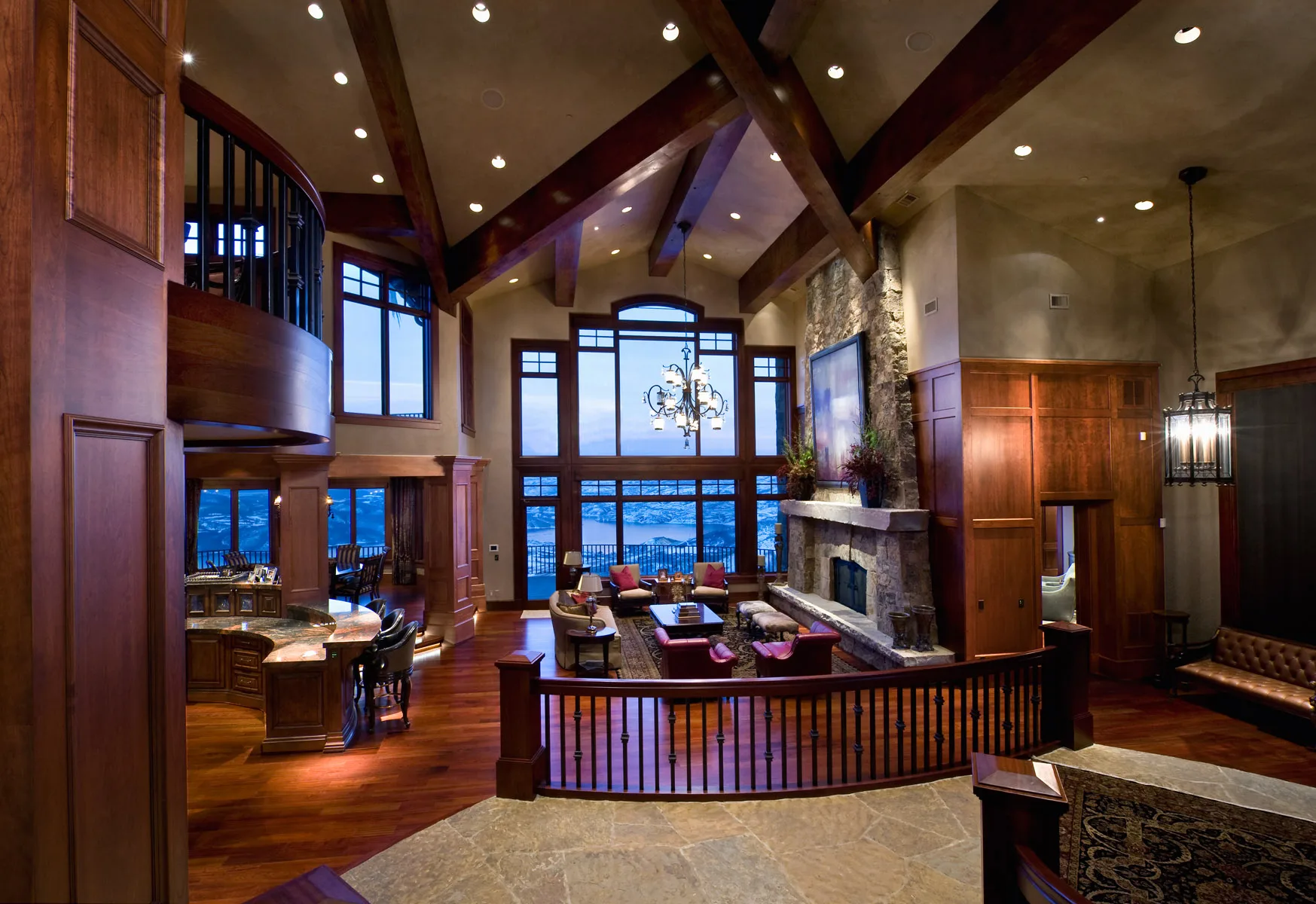 Great room with tall windows, a stone fireplace, leather furniture and mountain views