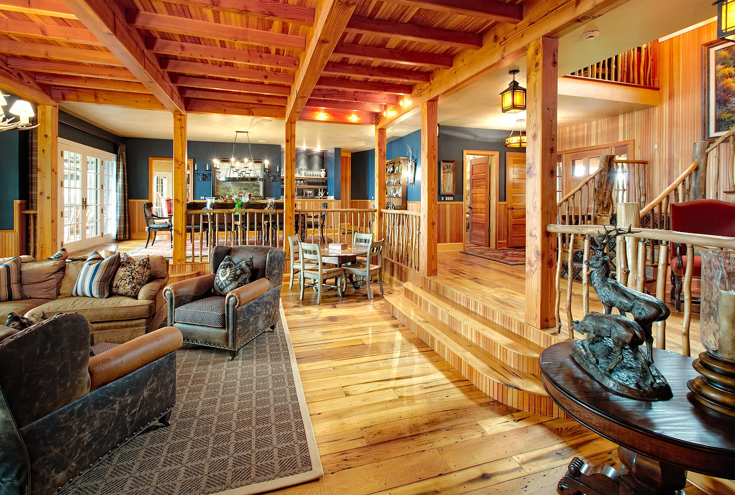 Great room with exposed wood ceiling beams, a stone fireplace and an open loft above