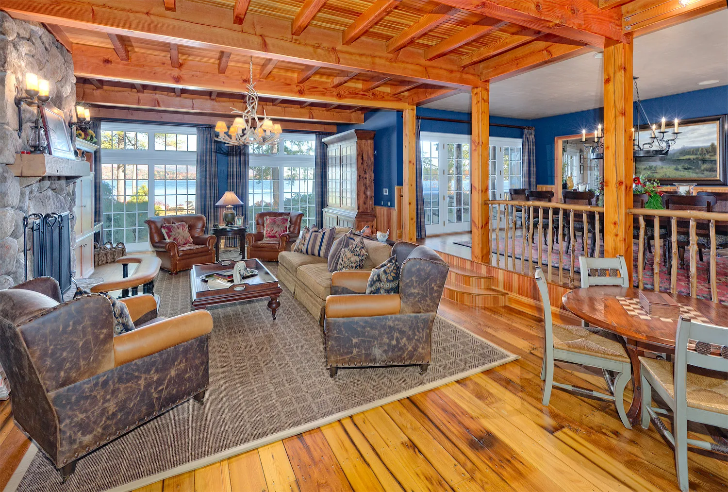 Living room with a stone fireplace, leather furniture and glass doors to the outside