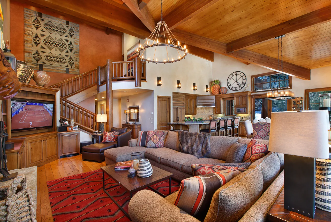 Open kitchen and living area with a wood beam ceiling and a round chandelier