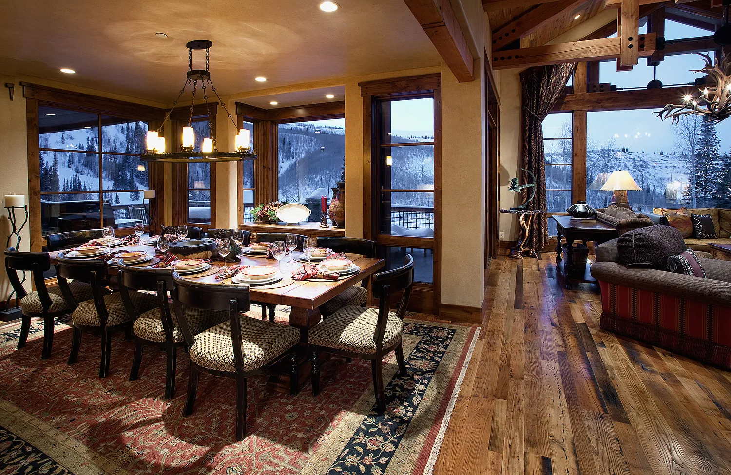 Open living and dining area with heavy timber trusses and large windows showing mountain views
