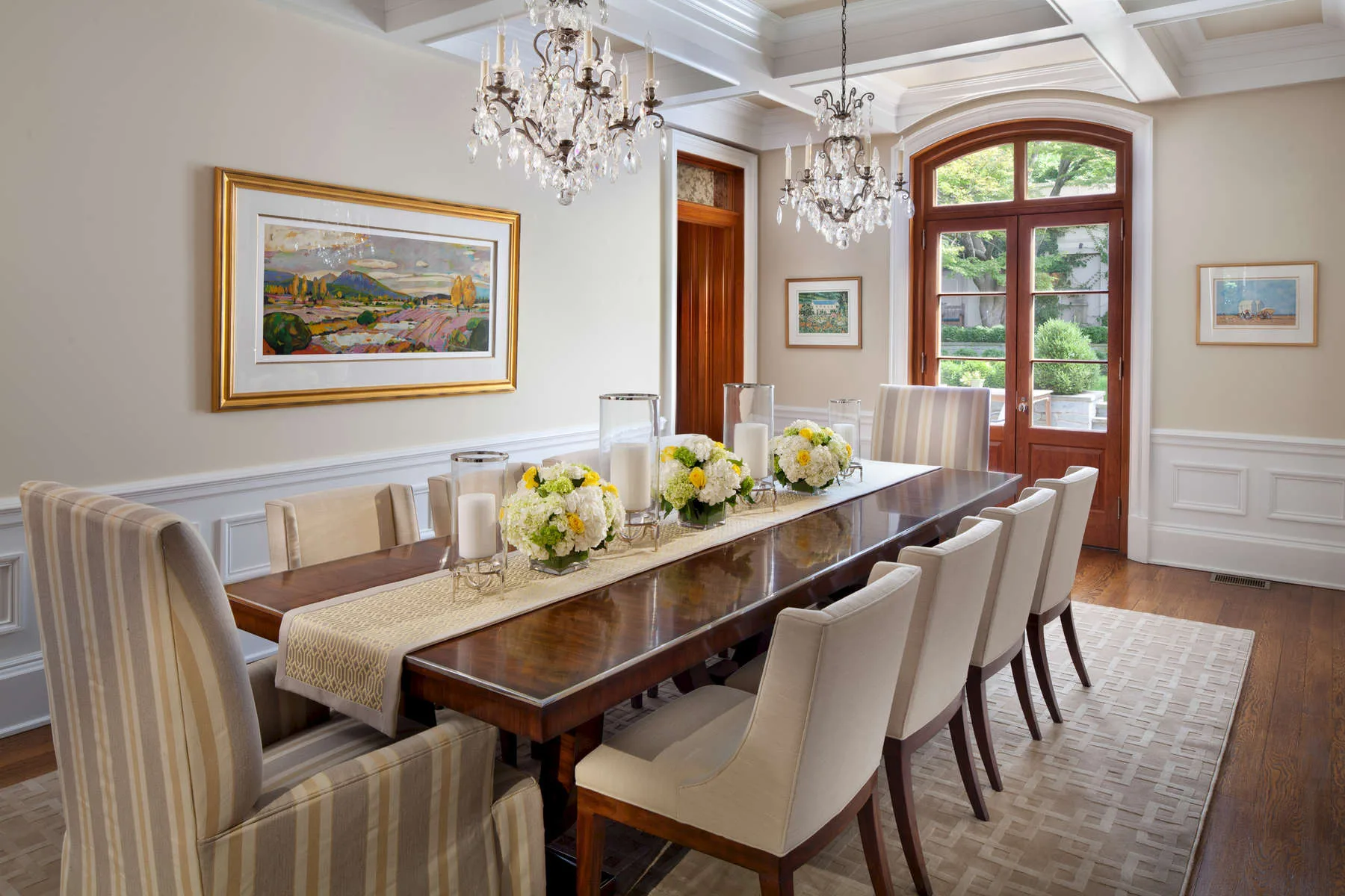 Dining room with a long table, white upholstered chairs and a crystal chandelier