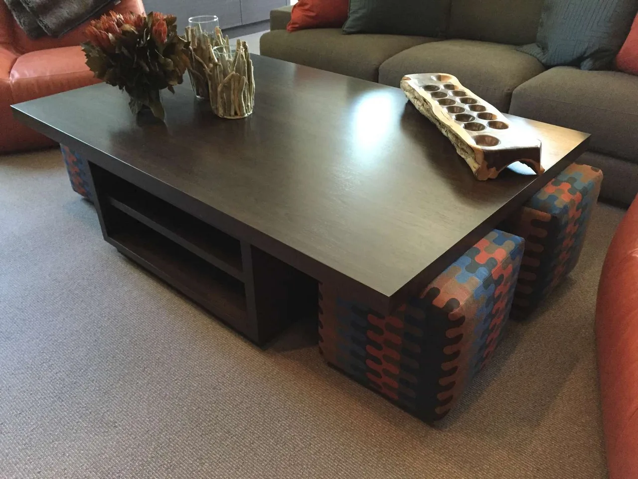 Custom coffee table with woven storage ottomans tucked underneath and a remote on top