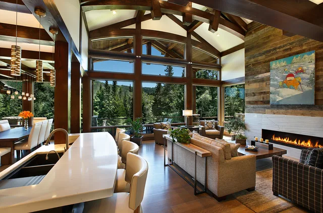 Mountain Modern: Kitchen with a white waterfall-edge island, cluster pendant lights and a vaulted timber ceiling with a glass wall