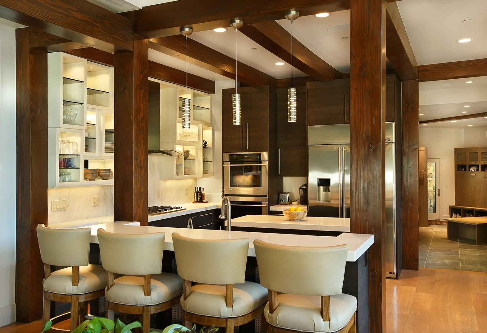 Wet bar with cream bar stools, dark wood cabinetry and pendant lighting