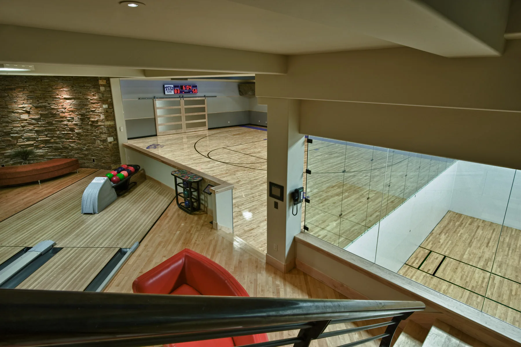 Indoor half sport court with a glass railing overlook from an upper level