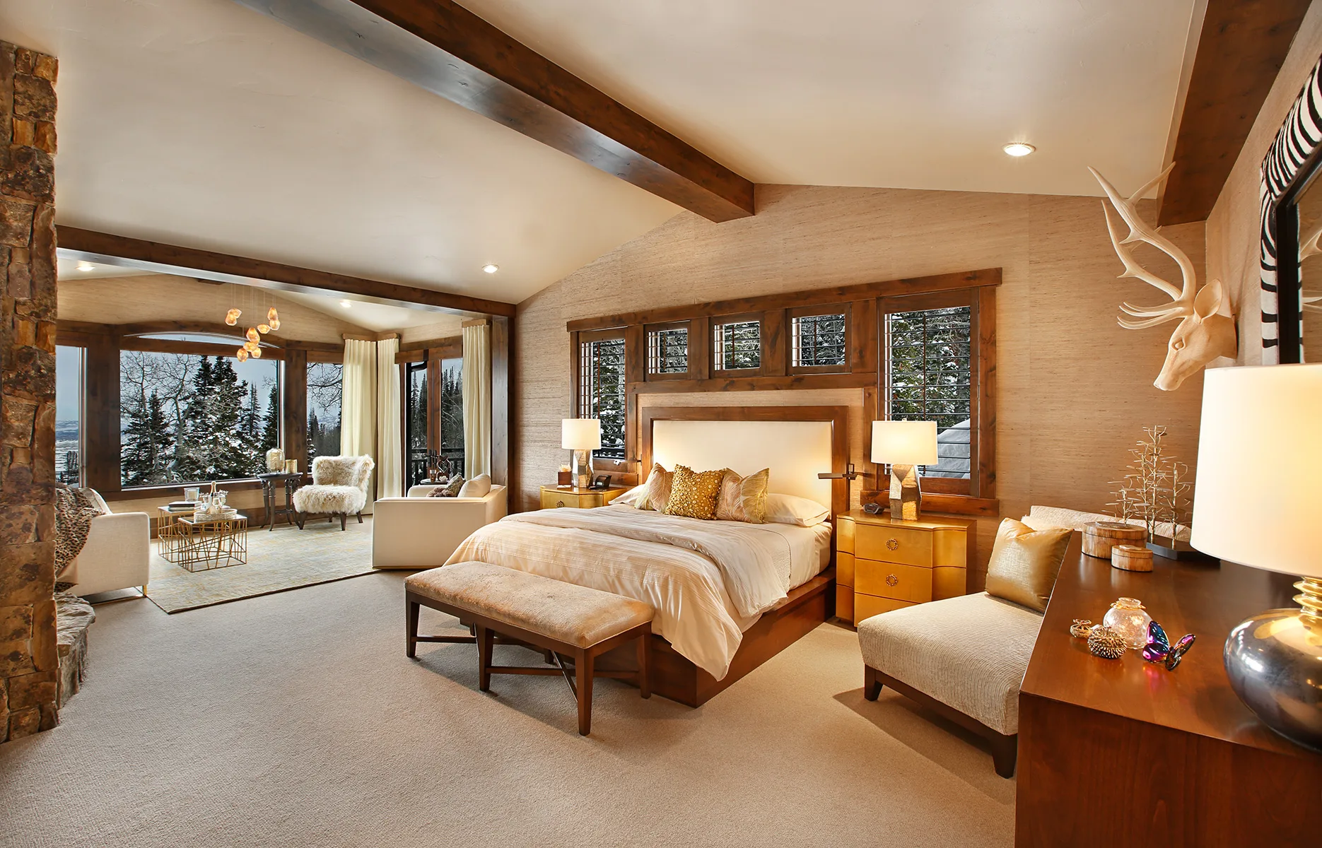 Bedroom with a wood bed frame, deer antler art above the headboard and a timber beam ceiling