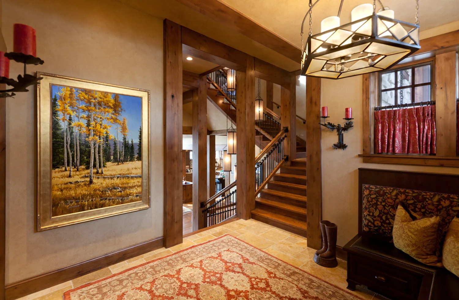 Entry foyer with a console table, chandelier, lit candles and a red runner rug