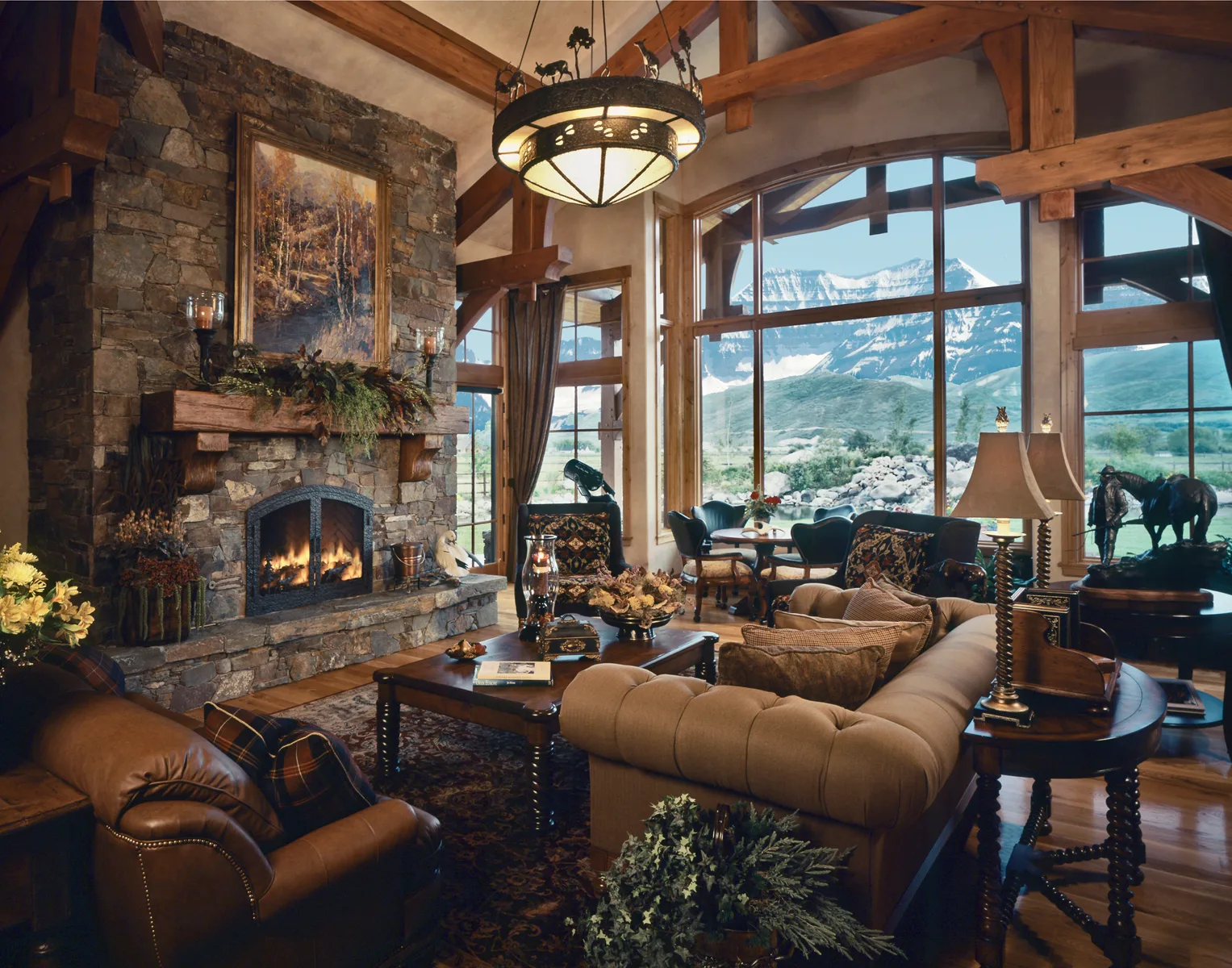 Great room with floor-to-ceiling windows, a stone fireplace, leather furniture and a mountain view