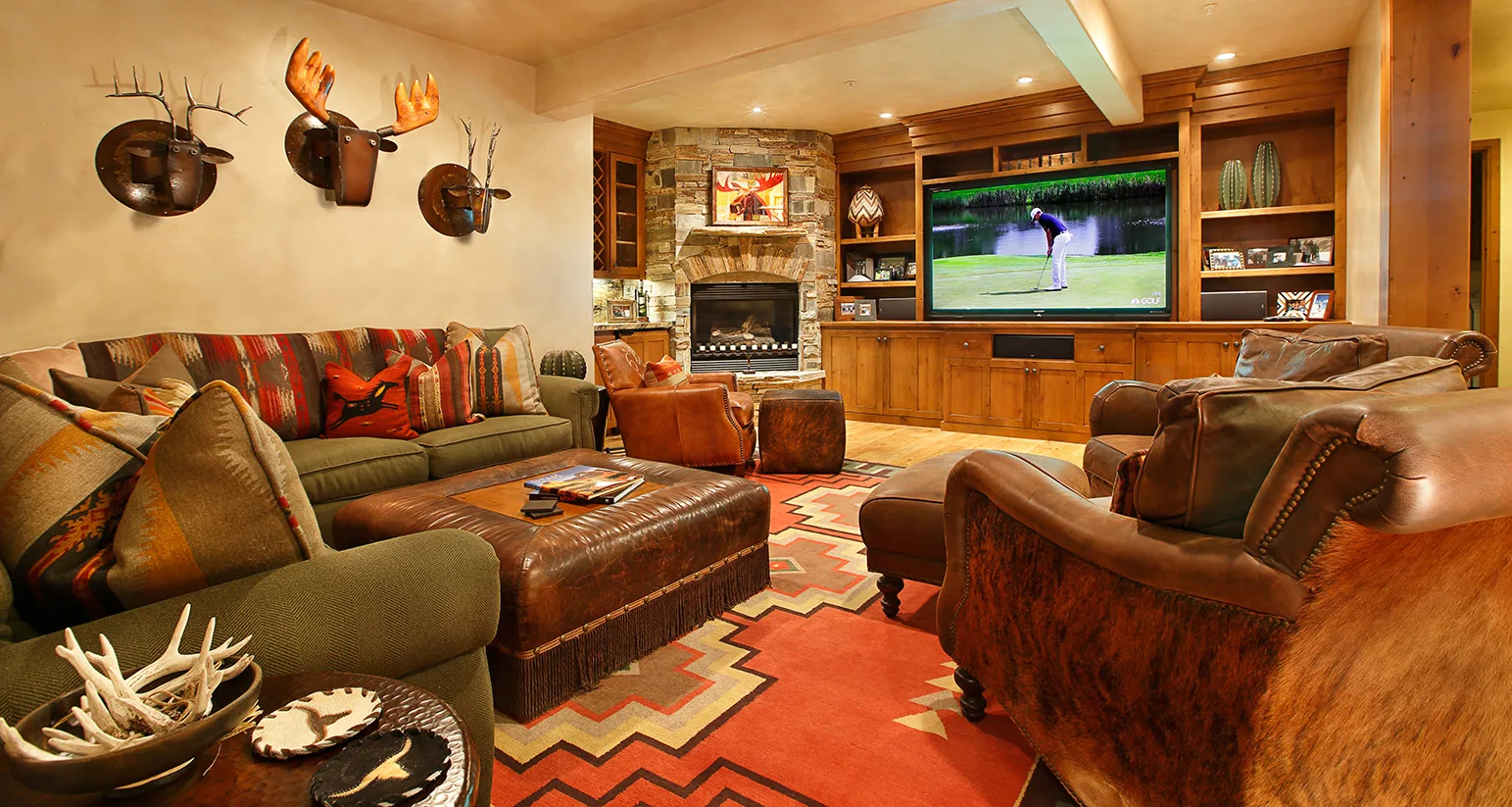 Living room with antler and taxidermy mounts on the wall, a patterned sofa and a fireplace