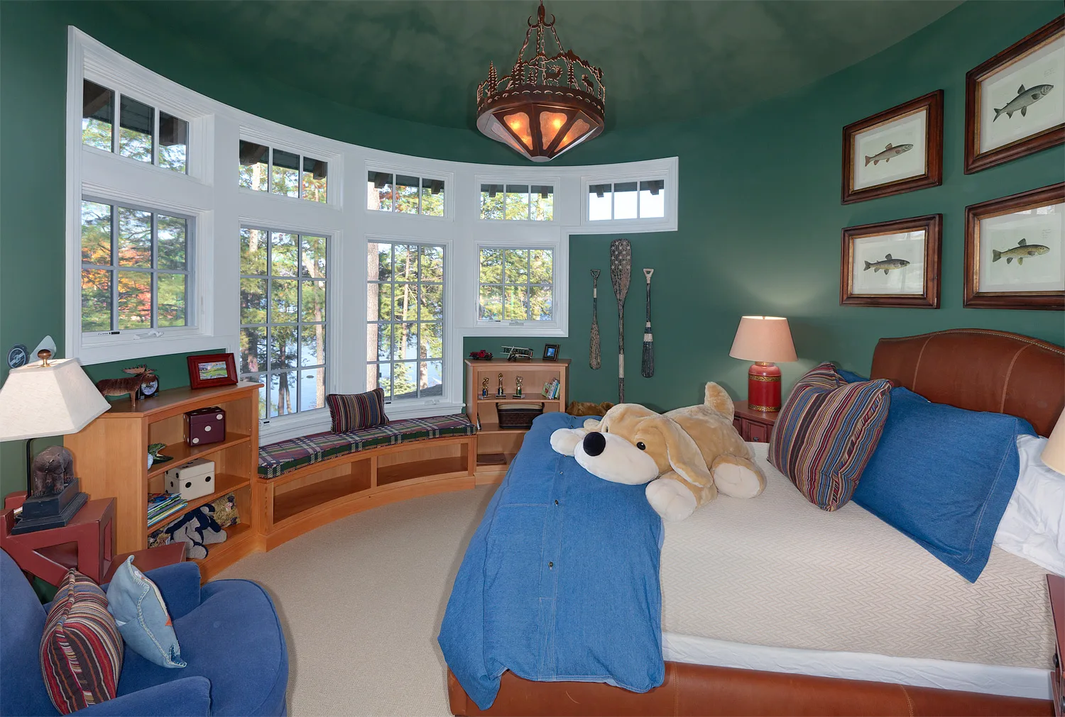 Child's bedroom with teal walls, built-in bunk-style beds and a stuffed animal on the pillow