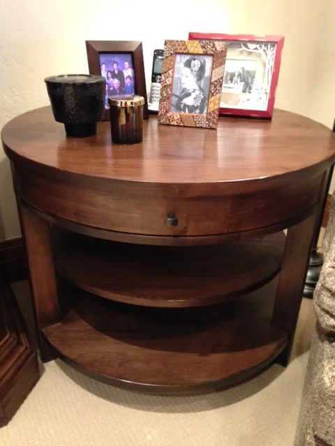 Round wood side table with framed photos and a candle on top