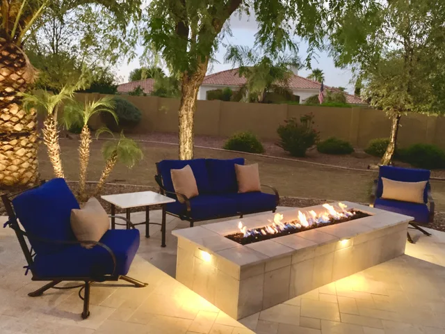 Linear fire pit at dusk with blue seating on travertine pavers