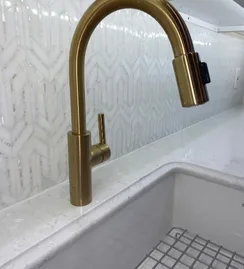 Brass pull-down faucet against patterned tile